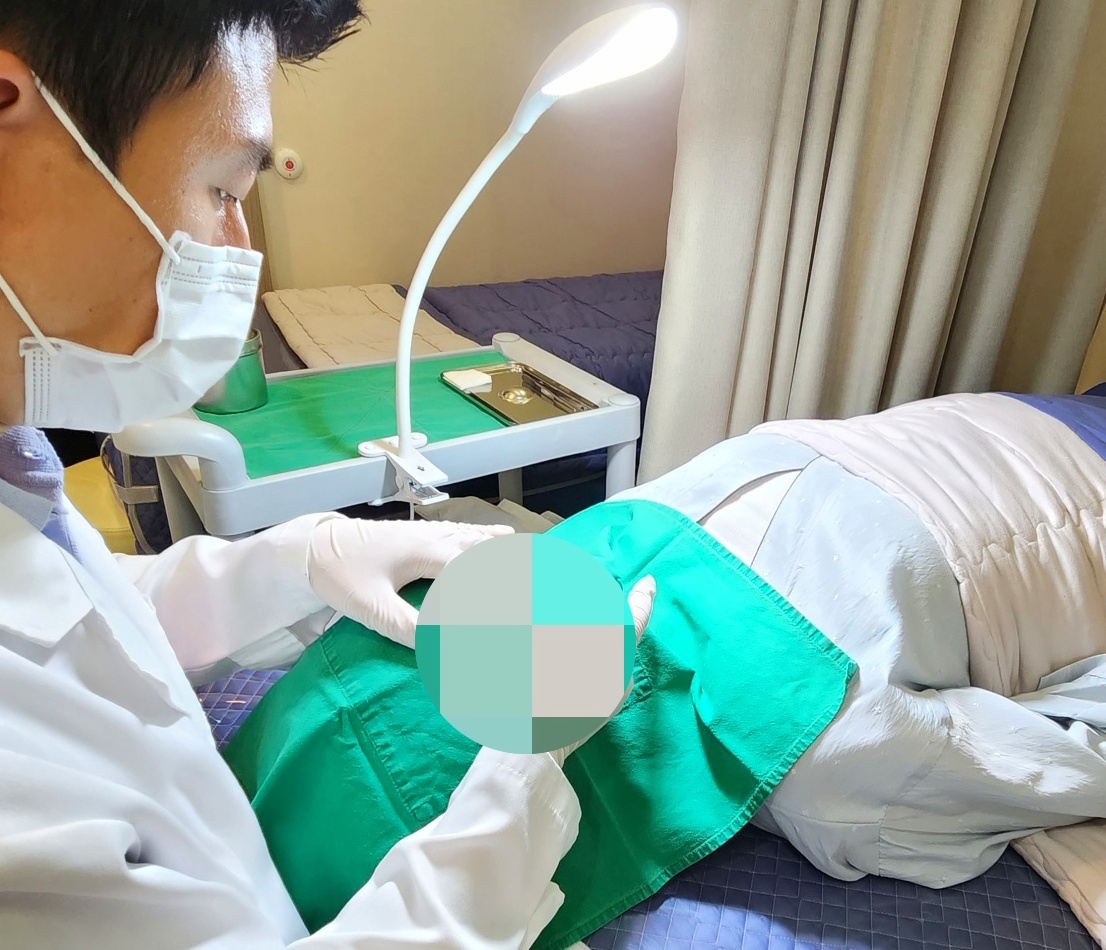 녹색 시술포를 덮고 조명 아래서 점 시술을 진행하는 원장의 치료 장면